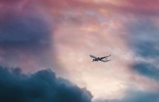 white plane flying over gray clouds